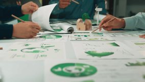 A diverse team collaborates on eco-friendly project planning, reviewing charts and graphs in a modern workspace filled with green materials and innovative ideas. SACTR - Powered by Shutterstock - Get 15% off with code: PIKWIZARD15