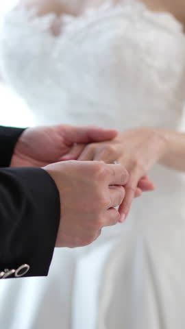 Close up of Romantic groom putting wedding ring on bride finger, elegant asian couple sharing love on special ceremony day
