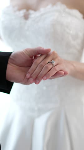 Close up of Romantic groom putting wedding ring on bride finger, elegant asian couple sharing love on special ceremony day
