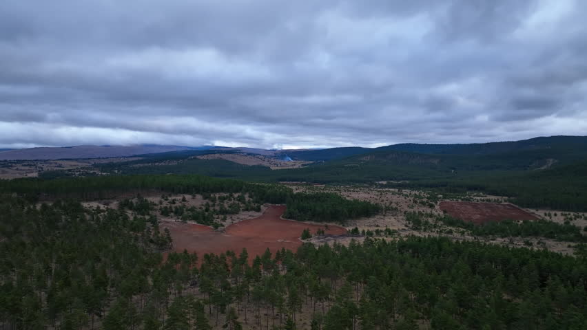 erial Mountain Landscape Under Heavy Clouds with Smoke in the Distance