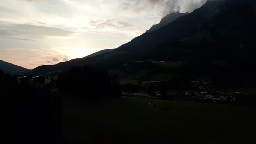 Aerial view of the mountains shrouded in a veil of twilight, the sun casting a golden hue over the landscape, Leogang, Salzburg, Austria.