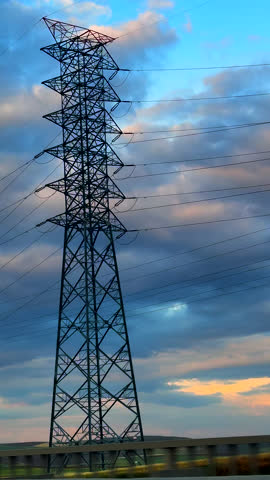 Vertical background of electric tower in a road. Sunset time with cloudy sky. Energy and electricity concept high quality background. 