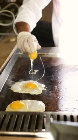 Chef prepares delicious breakfast on griddle, cooking eggs on restaurant griddle for meal, culinary experience, healthy cuisine, breakfast concept for cafe menu