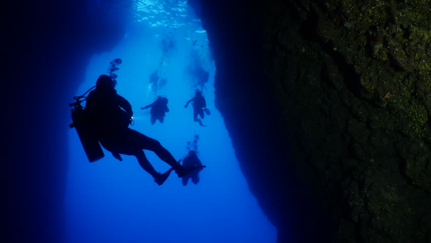 scuba divers are starting a cave dive underwater