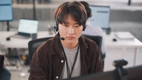 In a diverse corporate environment, an Asian tech consultant communicates with clients through headset and computer, providing business support and technical assistance with confidence. - Powered by Shutterstock - Get 15% off with code: PIKWIZARD15