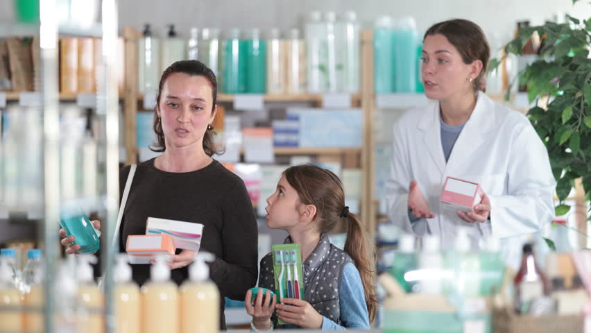 Happy middle-aged woman with daughter choosing different products and female pharmacist helping her in chemistry. High quality 4k footage