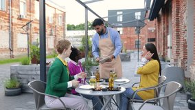 A server taking an order from customers at an outdoor restaurant. The customers are smiling and looking at the tablet. - Powered by Shutterstock - Get 15% off with code: PIKWIZARD15