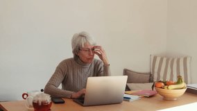 Focused older woman working remotely on her laptop, enjoying a cup of tea. She embodies productivity and the modern senior lifestyle. - Powered by Shutterstock - Get 15% off with code: PIKWIZARD15