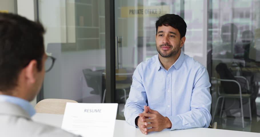 Young Hispanic man, vacancy candidate answers questions asking him HR manager sitting together at table in meeting room, shaking hands, accomplishing job interview successfully. Hiring, recruitment