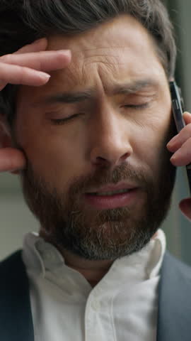 Vertical view unhappy frustrated Caucasian middle-aged business man talking mobile phone call failure upset in office worry stressed 40s businessman male talk smartphone problem suffering headache