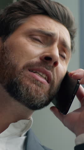 Vertical view unhappy frustrated Caucasian middle-aged business man talking mobile phone call failure upset in office worry stressed 40s businessman male talk smartphone problem suffering headache
