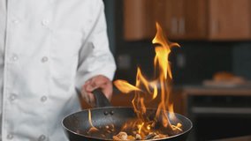 Chef Flambé Cooking in Slow Motion. Professional chef tossing flaming vegetables and shrimp in a hot pan. Gourmet stir-fry and fine dining concept in a restaurant kitchen. - Powered by Shutterstock - Get 15% off with code: PIKWIZARD15