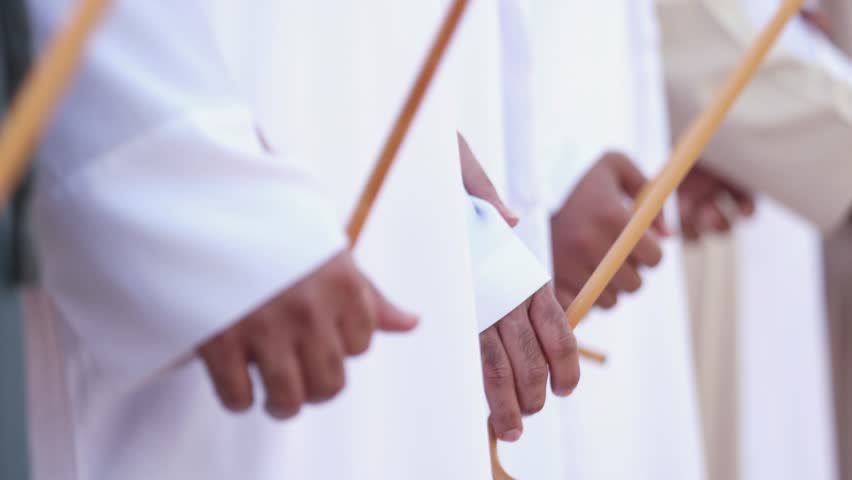 Traditional Emirati al Ayala male dance, cultural UAE heritage. Hands in frame.