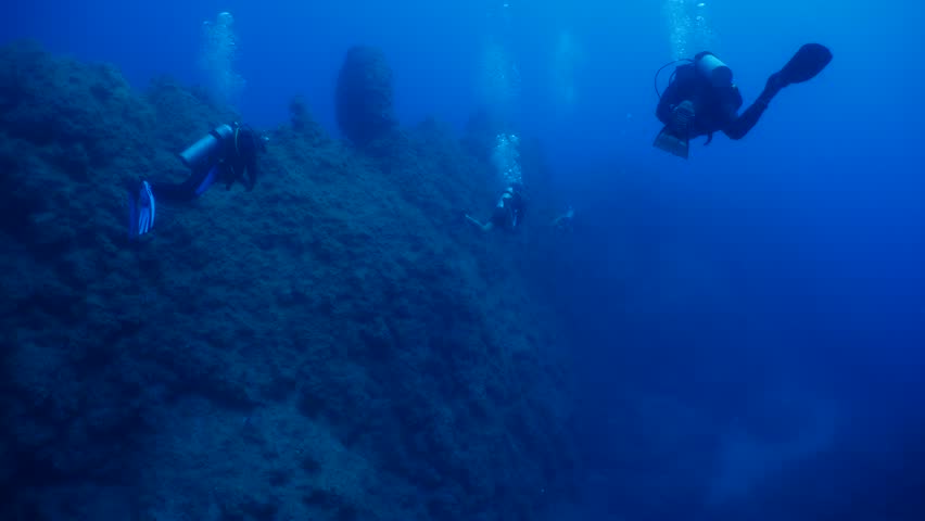 scuba divers are swimming next to walls underwater wall dive