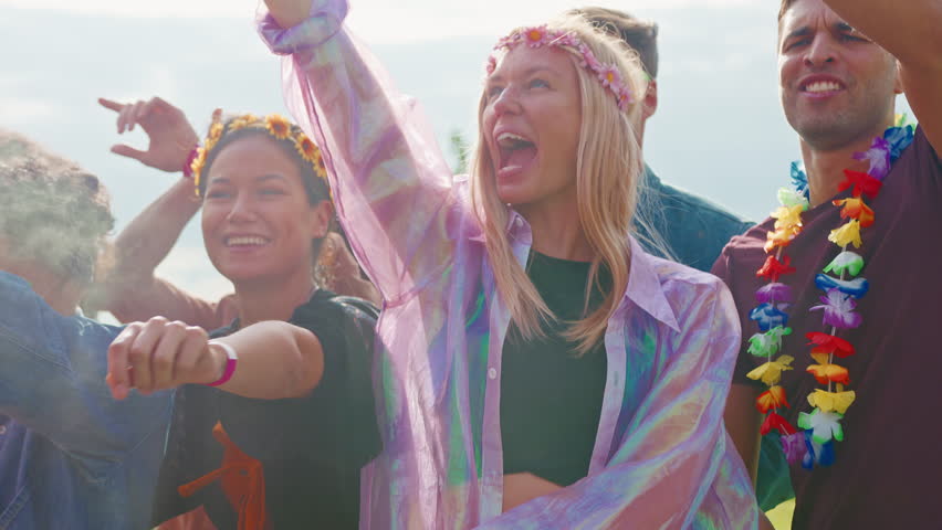 Group of young female friends dressed up and wearing headdresses walking through music festival site- shot in slow motion
