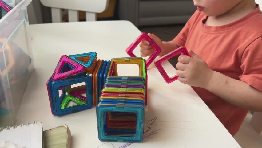 A child joyfully engages in play with a variety of colorful magnetic building blocks, nurturing their own creativity