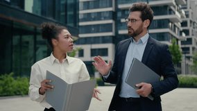 Two multiracial business colleagues partners multiracial African American woman girl female businesswoman talking serious discuss project startup with Caucasian man guy male businessman walking city - Powered by Shutterstock - Get 15% off with code: PIKWIZARD15