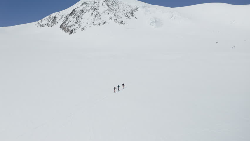 Two freeriders ski tour up the majestic Alphubel with their guide, then descend through glacial terrain surrounded by crevasses and seracs in the high alpine landscape of Saas-Fee.