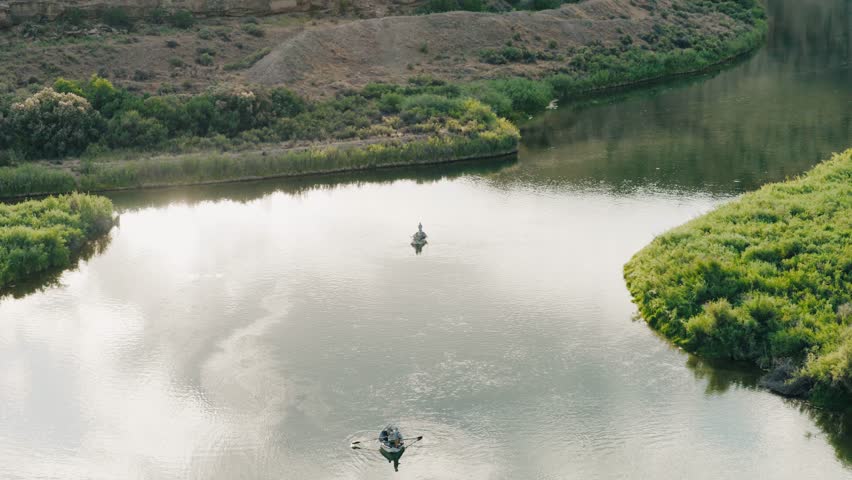 Aerial pull away shot of two guide boats fly fishing on the San Juan river. The sun beaming on the water.