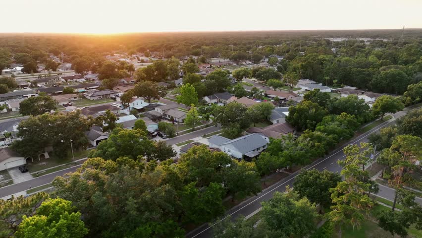Golden sunrise at horizon of quiet American neighborhood in Florida. Noble houses and villasin suburbia of Brandon, Florida. Aerial flight shot. Car on street in the morning.