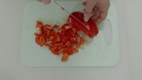 Chef slicing red bell peppers on white cutting board, creating uniform small pieces with precise culinary skill and sharp knife for fresh meal preparation - Powered by Shutterstock - Get 15% off with code: PIKWIZARD15