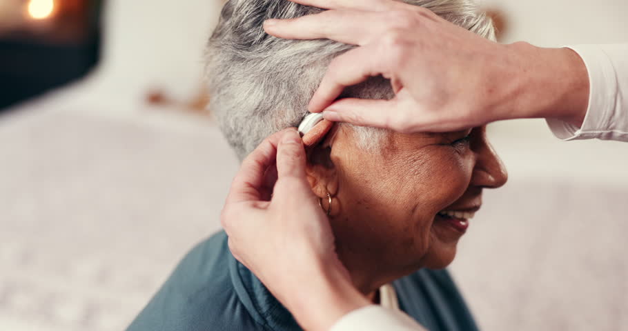 Healthcare, nurse and helping old woman with hearing aid, nursing home or installation of equipment. Happy, caregiver and assistance for elderly person with tech to amplify sound and communication
