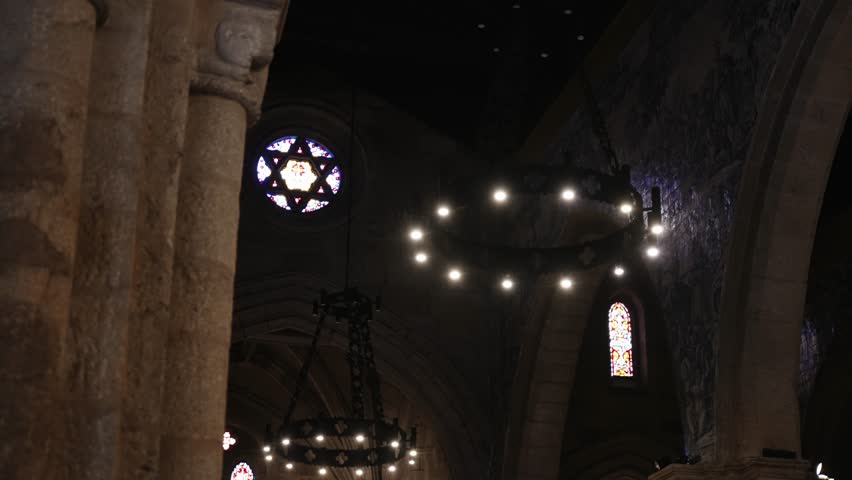 interior of a stone church with glowing chandeliers and a vivid star-shaped stained glass window