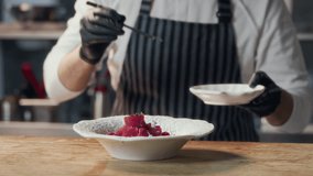 Zoom out shot of male chef garnishing tuna fillet cubes with edible flowers on plate before serving in fine dining restaurant - Powered by Shutterstock - Get 15% off with code: PIKWIZARD15