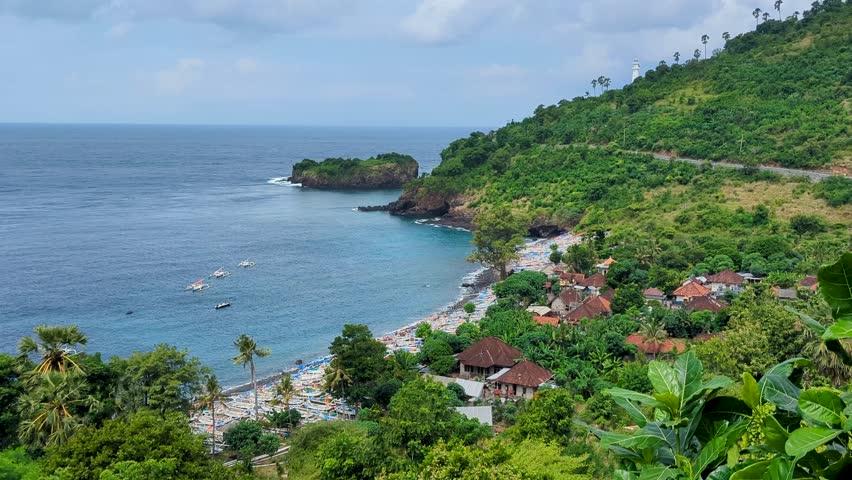Scenic aerial view of sheltered bay, fishing boats, ocean, and green landscape with glimpse of Gili Selang Lighthouse at Easternmost Point of Bali, Indonesia