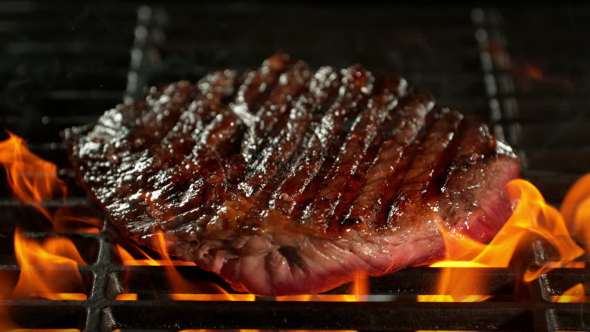 Super Slow Motion Shot of Tasty Beef Steak Meat Falling on Hot Grill with Flames at 1000fps