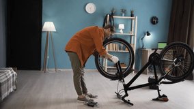 Female Cyclist Inserting Bicycle Wheel into Frame During Indoor Home Repair - Powered by Shutterstock - Get 15% off with code: PIKWIZARD15