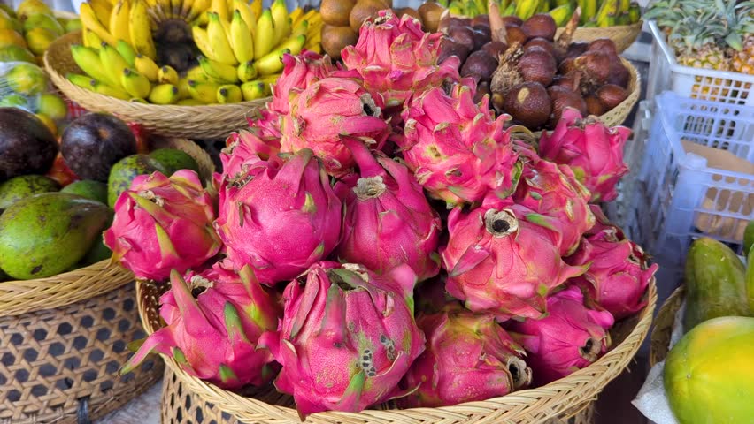 Closeup of exotic pink dragonfruit in Balinese wicker basket with other tropical fruits on market stall in Bali Indonesia