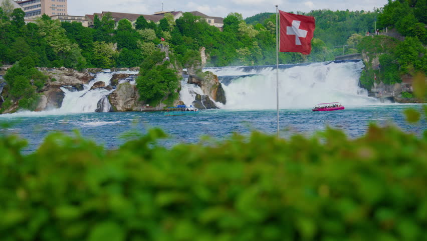 Switzerland Rhine Falls waterfall. Largest natural river waterfall Europe. Tourists sail by boat directly to the waterfall to feel the spray on themselves