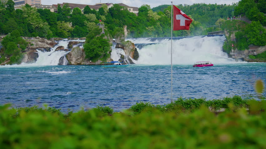 Switzerland Rhine Falls waterfall. Largest natural river waterfall Europe. Tourists sail by boat directly to the waterfall to feel the spray on themselves