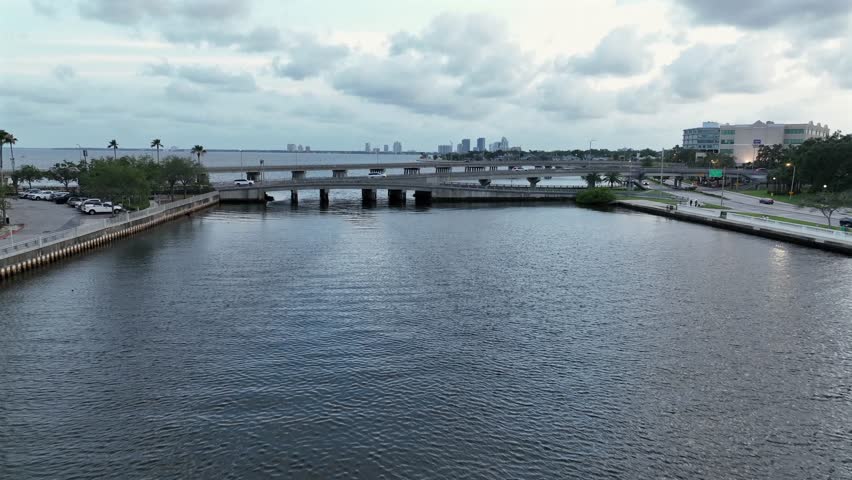 Aerial approaching shot of bridges with driving cars in Tampa, Florida at dusk. Bayshore with skyline in background. Wide shot. Cloudy day in USA.