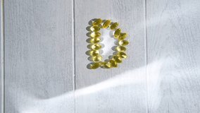 Yellow transparent capsules of vitamin d forming the letter d on a white wooden surface illuminated by sunlight, representing the importance of this vitamin for health and well-being - Powered by Shutterstock - Get 15% off with code: PIKWIZARD15