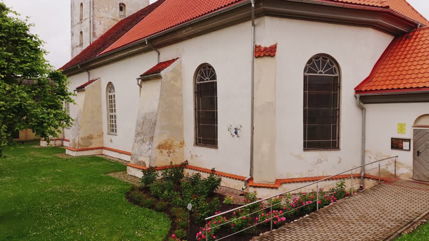 Vertical drone lift reveals ancient Lutheran church and small town under clouds
