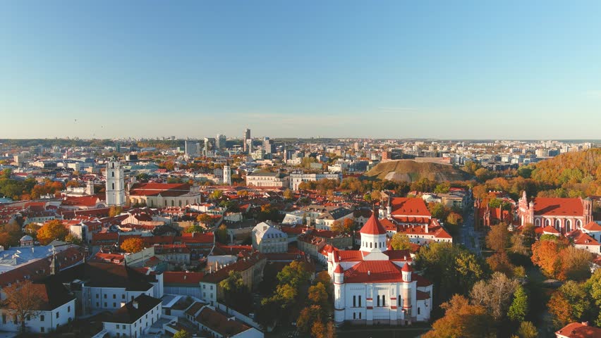 Beautiful aerial Vilnius city Old town panorama in autumn with orange and yellow foliage. Aerial sunny evening view. Cathedral of the Theotokos. Fall city scenery in Vilnius, Lithuania