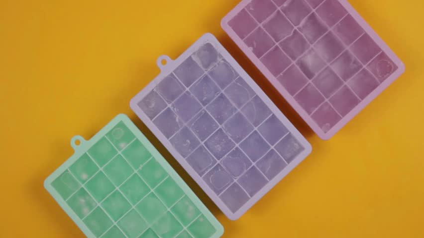 Frozen Ice Cubes in Colorful Silicone Trays on Yellow Background – Visual Concept of Freezing and States of Matter in 4K Ultra HD