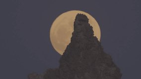 A de-focused full moon rises behind a rocky pinnacle outcrop in the desert night sky - Powered by Shutterstock - Get 15% off with code: PIKWIZARD15