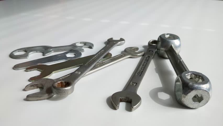 Woman choosing tool from multiple spanner tools on worktop, close up