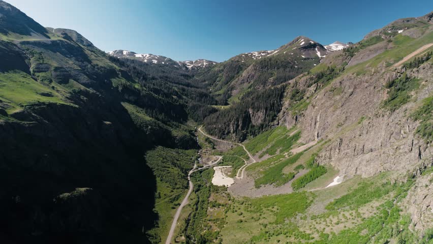 Aerial shot of a valley in the San Juan mountain range following a winding road.