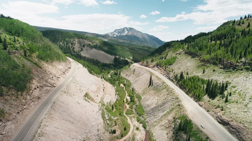Aerial push of a road that follows the mountains as a part of the San Juan mountain range.