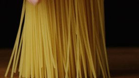 Spaghetti Falling and Breaking in Slow Motion. Uncooked pasta dropped on a wooden board against a black background. Italian food and cooking ingredient concept. - Powered by Shutterstock - Get 15% off with code: PIKWIZARD15