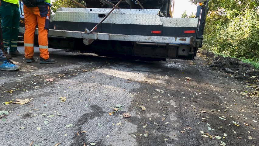 Asphalt Paver Lowering Platform and Preparing for Asphalt Paving at Road Renovation Construction Site