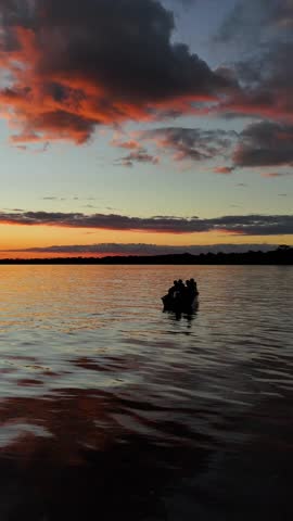 Peaceful sunset scene of people in a boat on the calm Amazon River in Peru, surrounded by tranquil waters and lush landscape