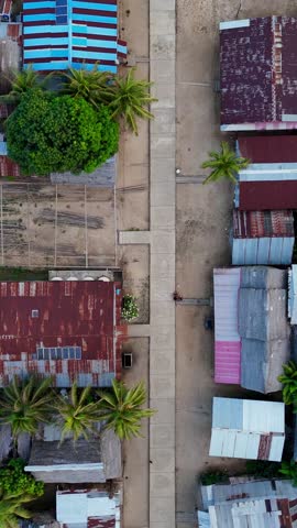 Aerial drone view of a remote Amazon rainforest village with a church, school, market, and several bars, surrounded by dense jungle canopy