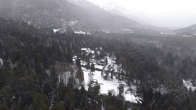 Drone captures a vast Patagonian forest blanketed by thick snowfall near Colonia Suiza, Bariloche. Snow-covered trees, cabins, and misty mountains frame the winter weather scenery from above. - Powered by Shutterstock - Get 15% off with code: PIKWIZARD15