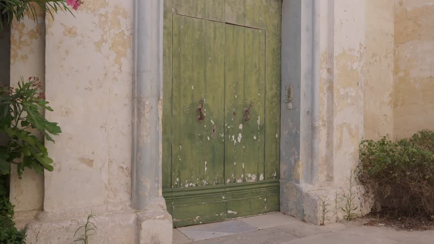 Rustic old wooden door with faded green paint in Mediterranean Malta