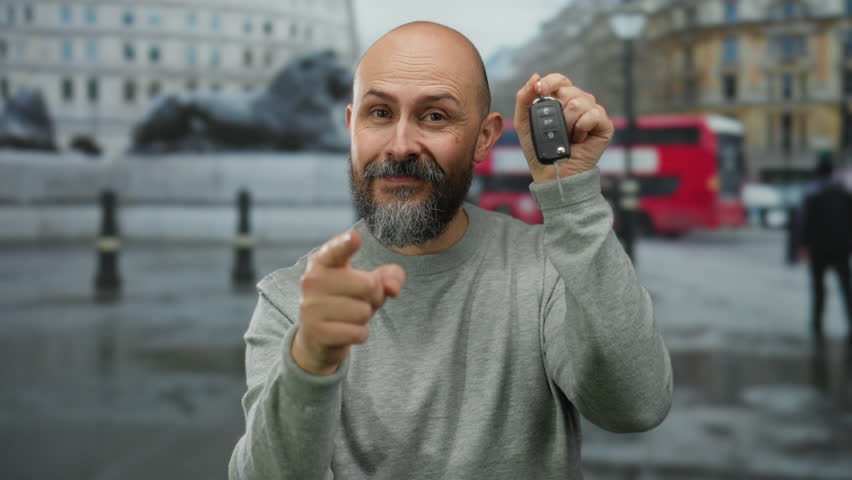Bearded man with tattoo shows car keys on urban street backdrop suggesting transportation acquisition in vibrant city setting and cultural lifestyle.